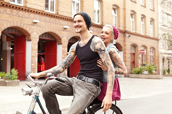 inhalt_ratgeber_tattoos Ein frisch tätowiertes Pärchen fährt Fahrrad.